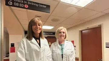 Kimberly Dever, MD and Kathleen Bruce stand outside the obstetrics emergency department