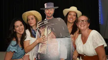 A group of women poses with a cardboard cutout of Clint Eastwood in wester attire