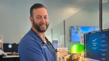 South Shore Health Urgent Care provider Benjamin Hixon, PA-C in front of computer monitor