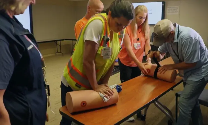 A worker from DPR Construction applies pressure to a prosthetic limb as a South Shore Health colleague looks on during a Stop the Bleed training session.